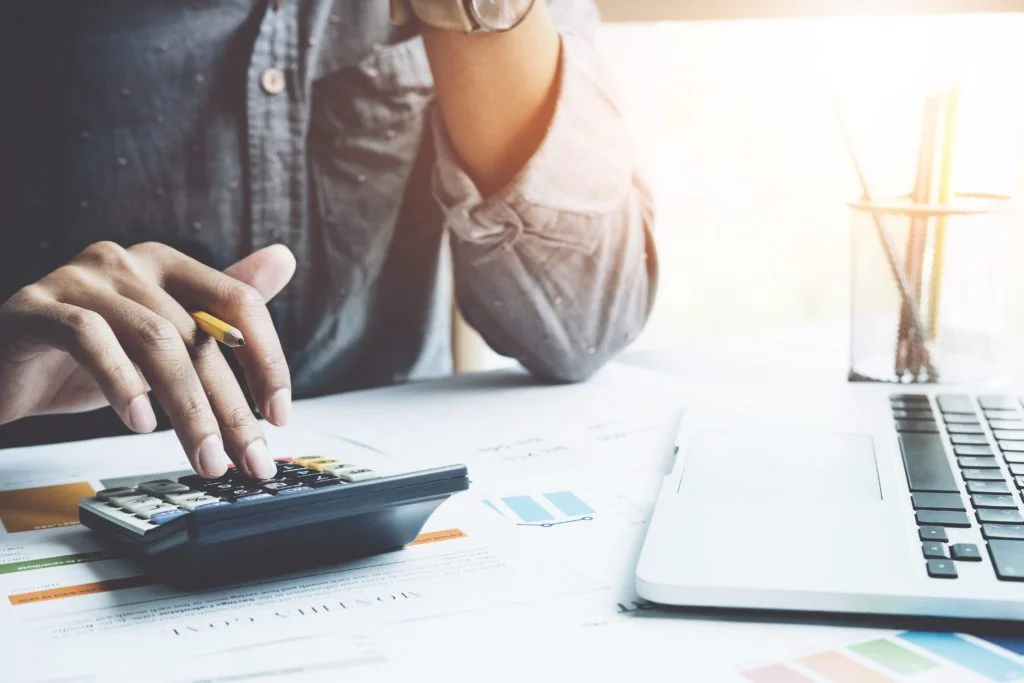 Accountant using a calculator and laptop