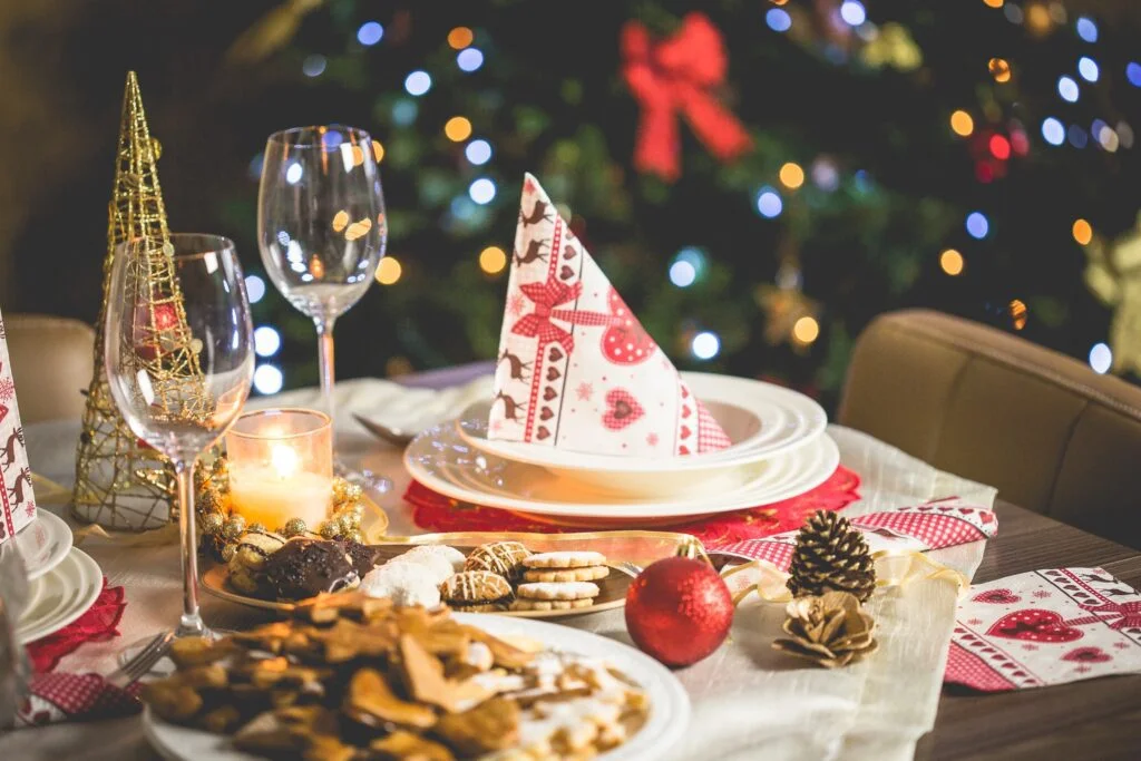 A Christmas table setting with a Christmas tree in the background, perfect for festive parties.