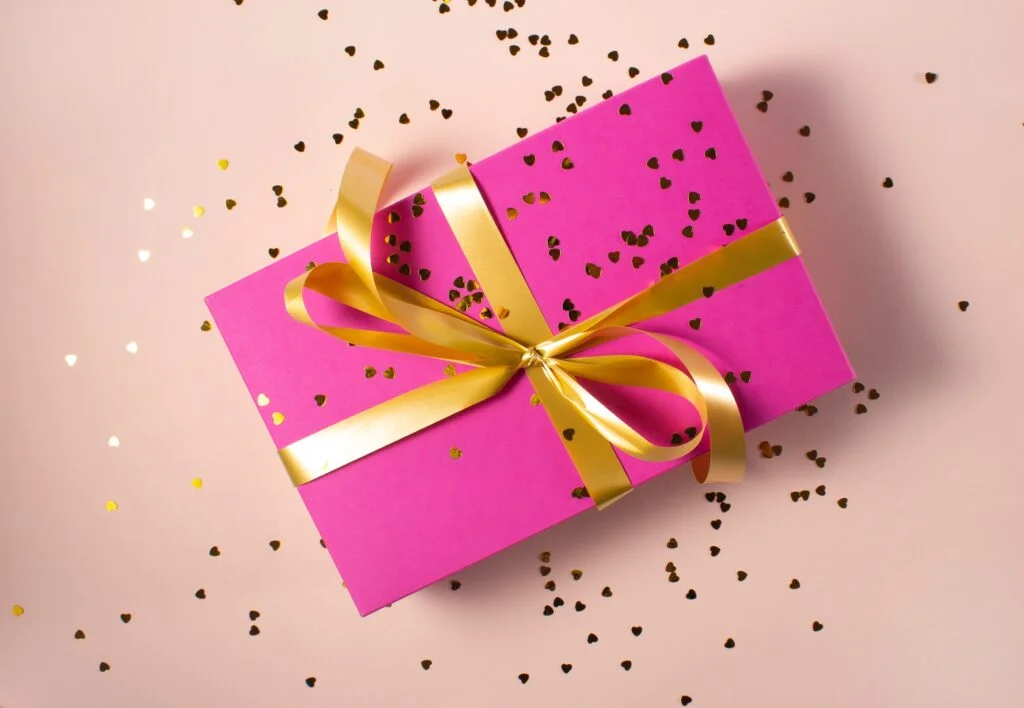 A pink gift box with gold confetti, perfect for Employee Gifts.