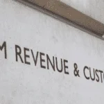 Hm revenue & customs sign on a building indicating VAT Return Filing procedures and potential penalties for non-compliance.
