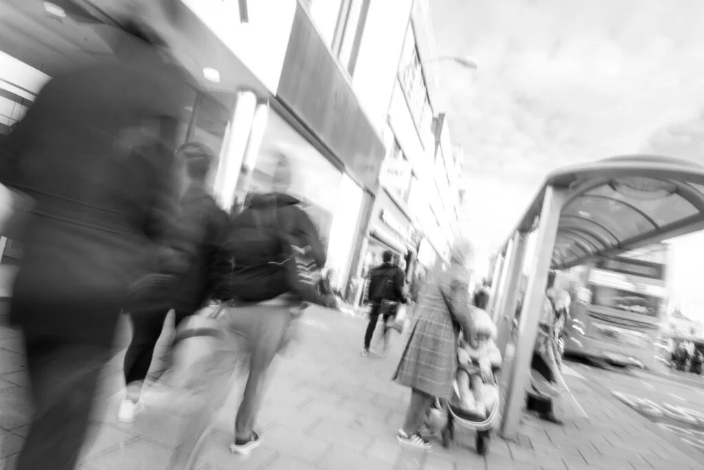 A black and white photo capturing people's movement along a busy street.