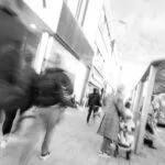 A black and white photo capturing people's movement along a busy street.