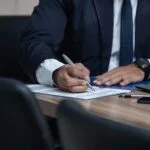 A businessman signing a document for inheritance tax planning at a desk.