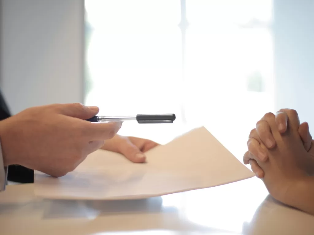 Person with pen handing paper to sign