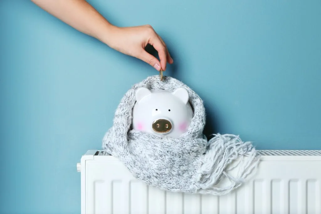 A hand putting coin into a piggy bank in a scarf