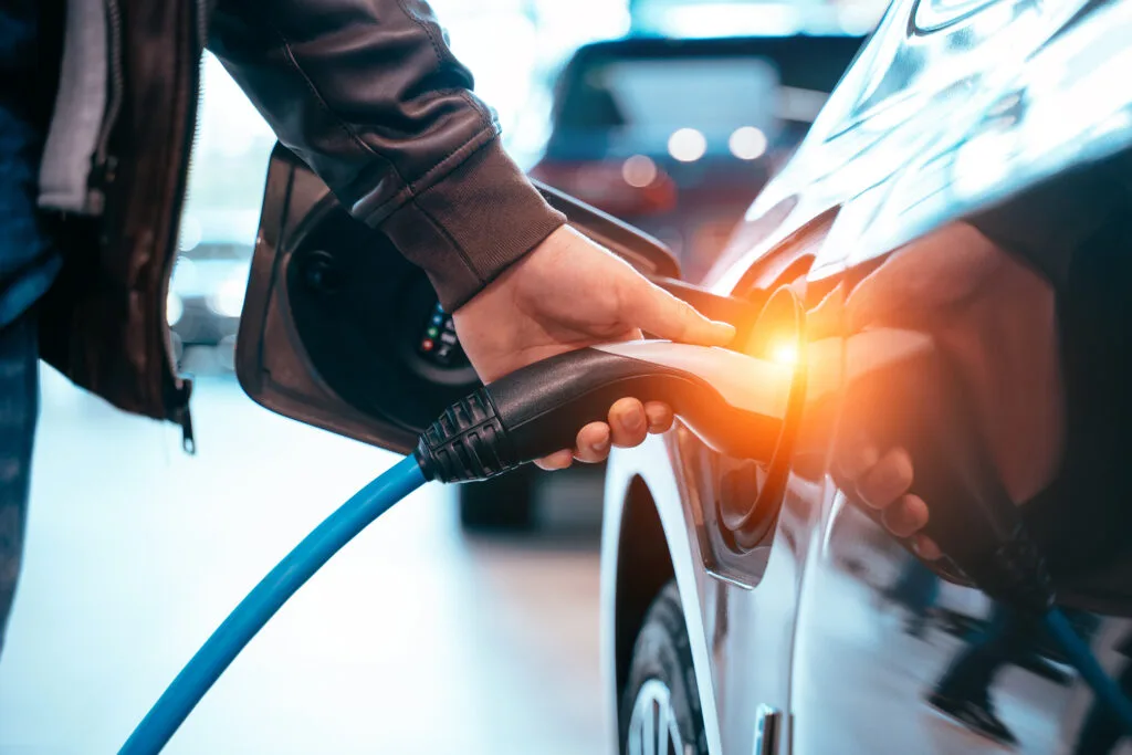 November 2025 Newsletter 4 Closes up Human hand is holding Electric Car Charging connect to Electric car