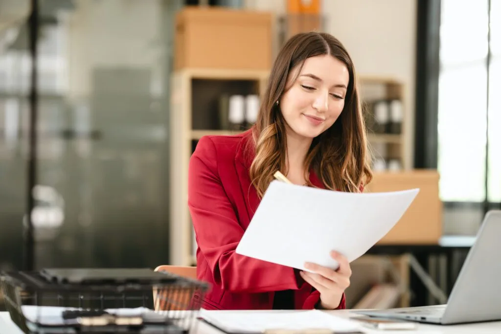 May 2026 Newsletter 2 Caucasian businesswoman, likely an accountant or CPA, smiling and holding a coffee cup while working on her laptop.