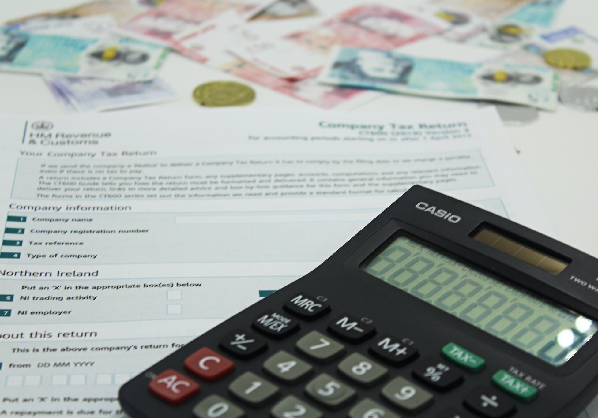 A calculator sits on top of a pile of money, perfect for accountants and limited companies.