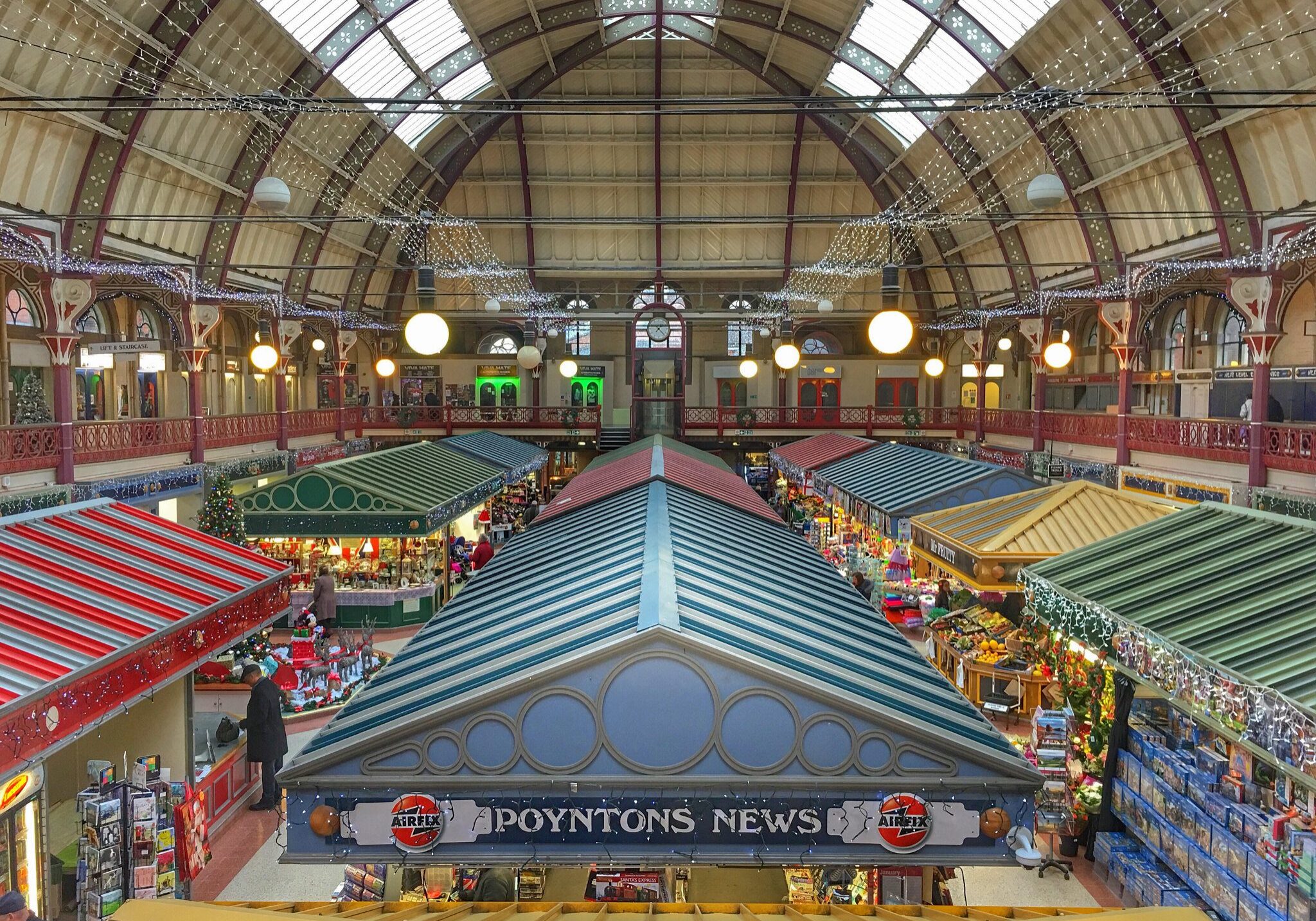 The inside of a large market with many stalls and awnings is abuzz with the activities of accountants and self-employed individuals.
