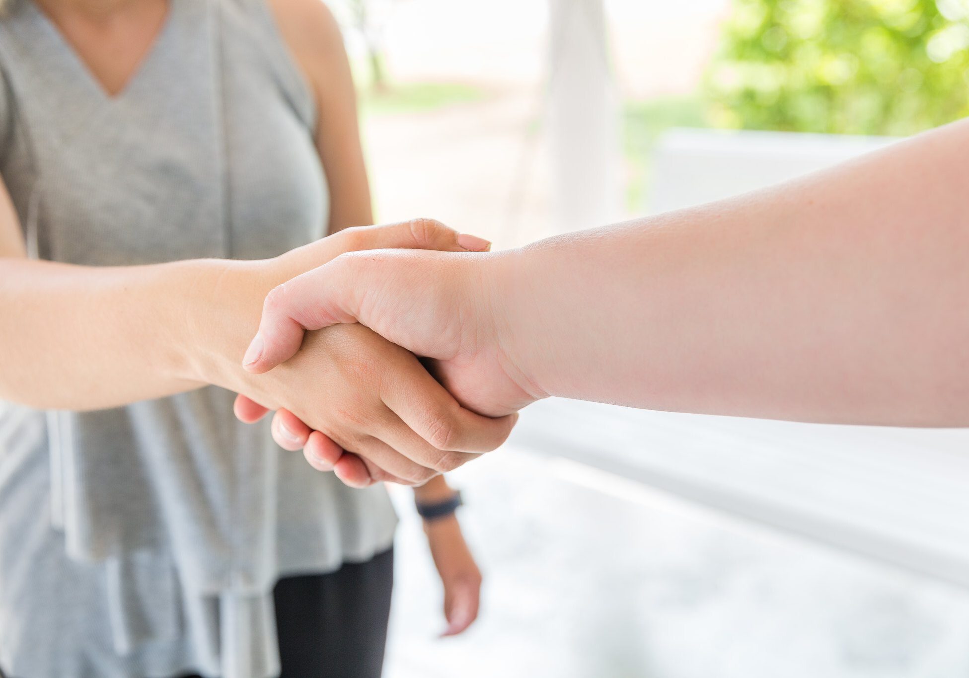 Two women, who are accountants, are shaking hands in celebration of their successful partnership.